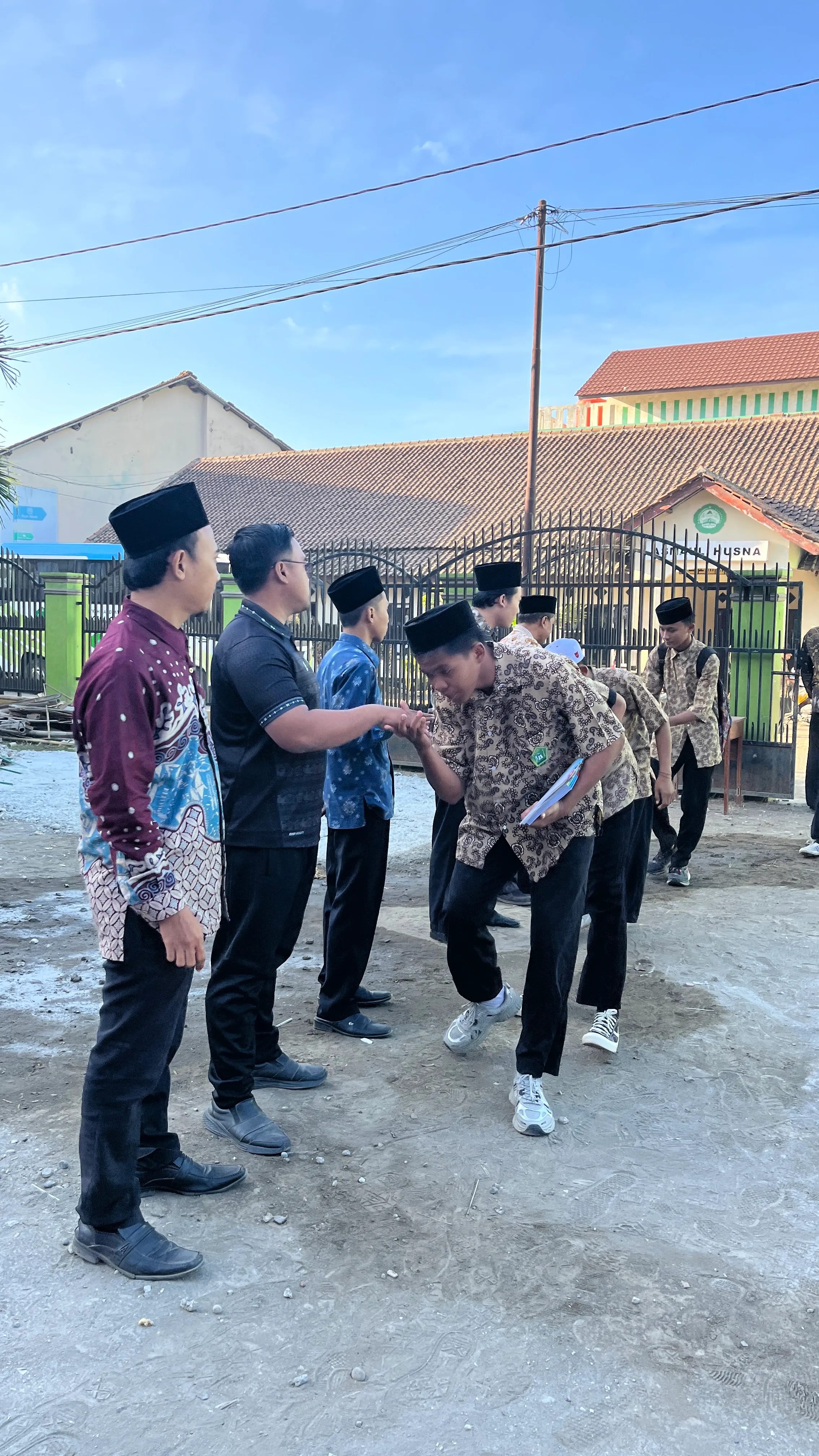 Guru MA MINAT menyambut dan bersalaman dengan siswa yang tiba di madrasah